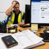Missed calls lose jobs for trades businesses as stressed Perth contractor handles unanswered customer enquiries in busy office workspace